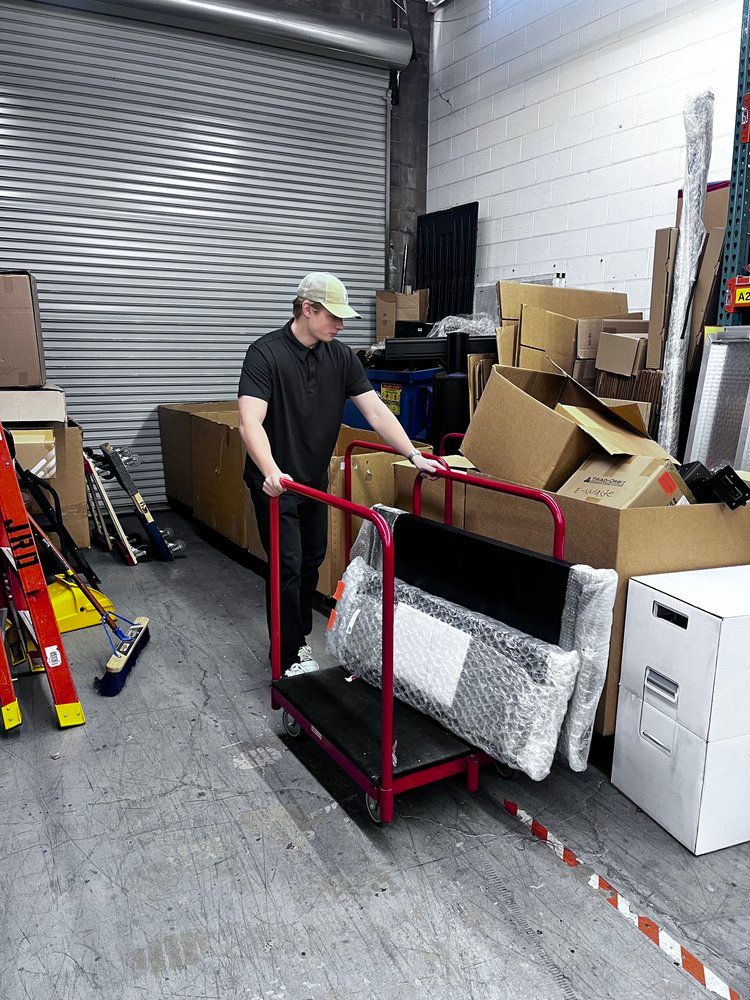 A man is pushing a cart with boxes on it in a warehouse.