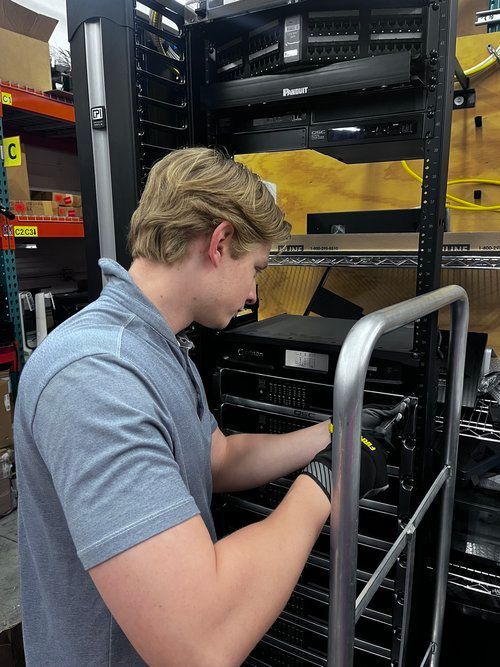 A man is working on a server rack in a warehouse