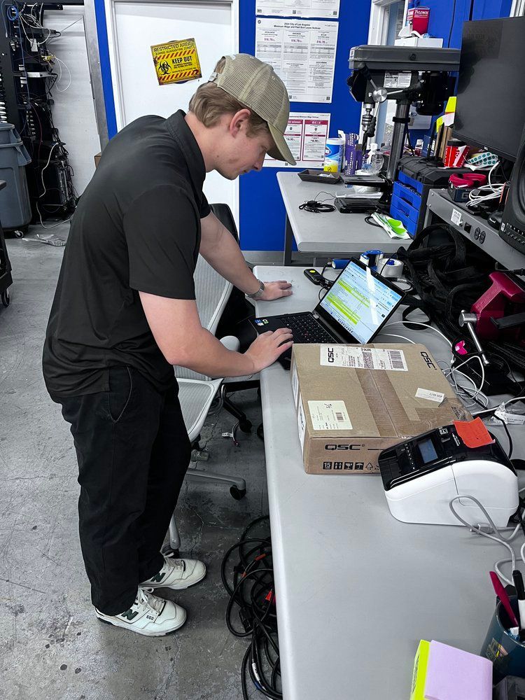 A man is standing at a desk using a laptop computer.