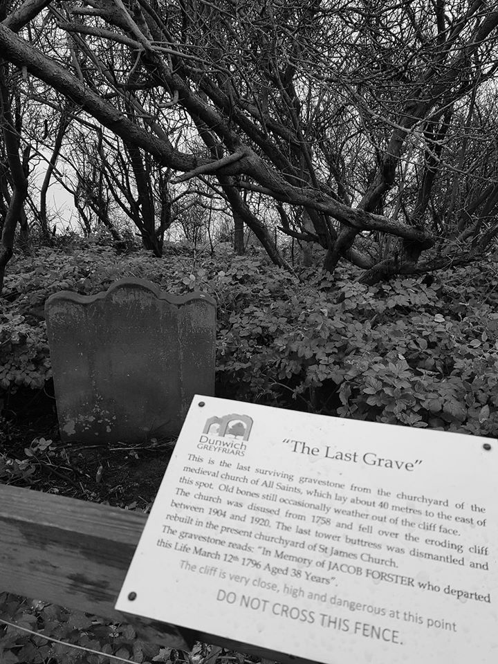Black and white photo of a grave with sign that says 