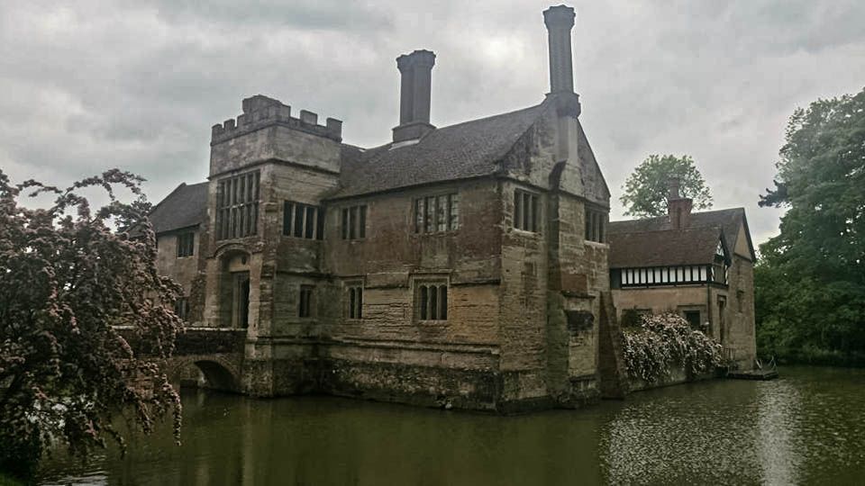 Stone manor house on a moat under an overcast sky.