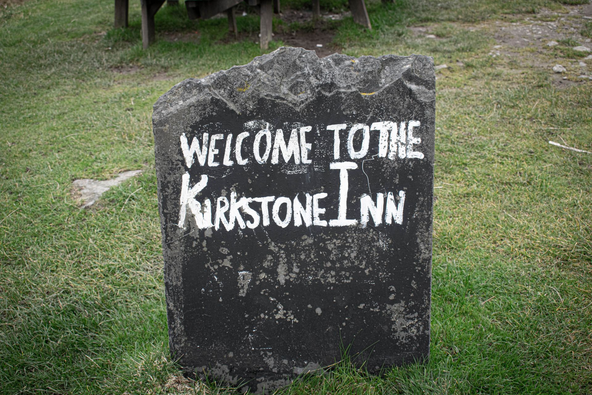 A gray, hand-painted sign that reads 