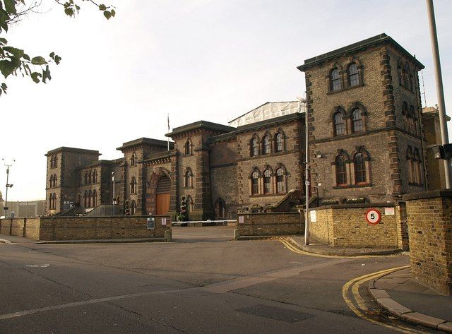 Stone prison building with towers, entrance gate, and surrounding road.