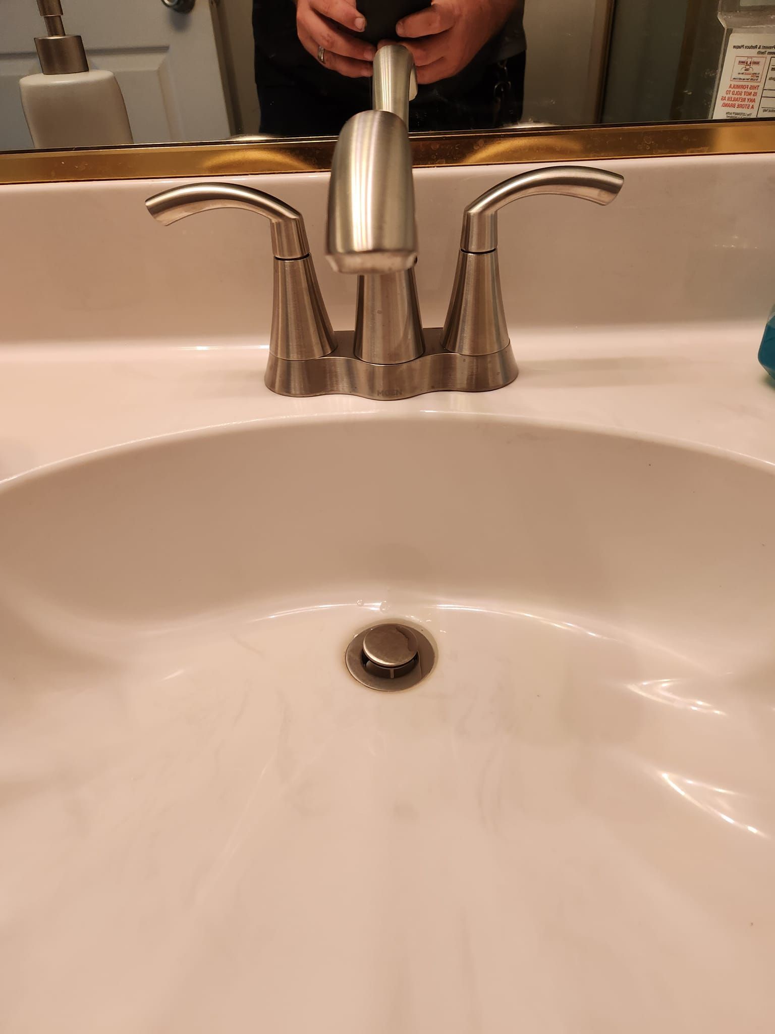 A brushed-nickel, two-handle bathroom faucet set over a white ceramic sink.
