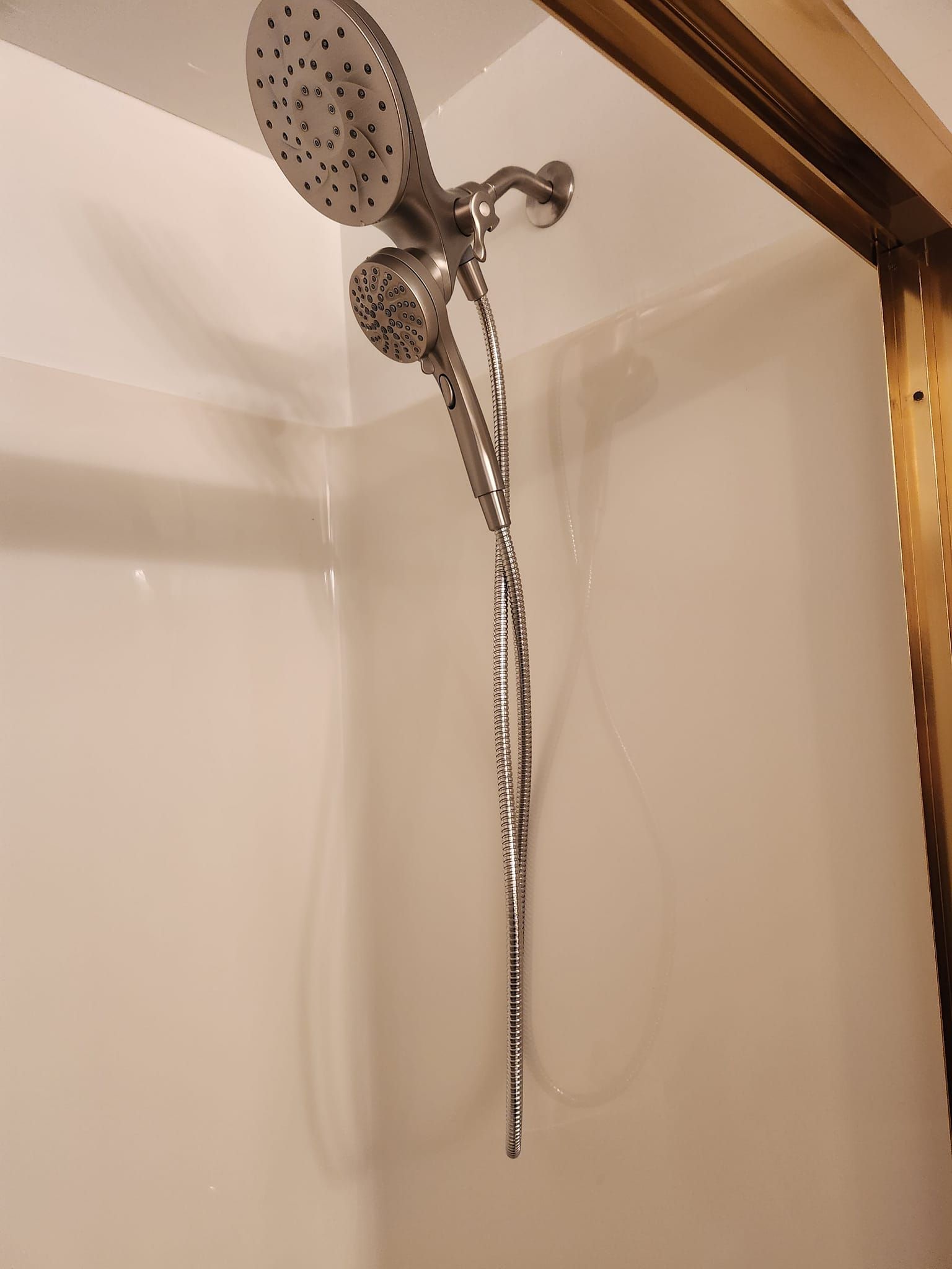 A dual shower head system with a chrome finish mounted on a white wall.