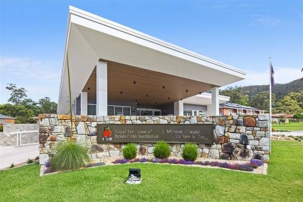 A Large Building with A Stone Wall and A Sign in Front of It — Nambucca Plumbing in Nambucca Heads, NSW
