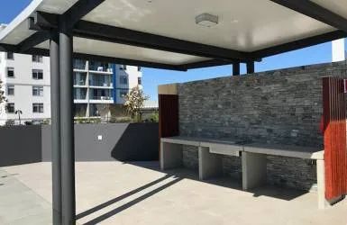 A Patio with A Grill and A Covered Area with A Building in The Background — Nambucca Plumbing in Nambucca Heads, NSW