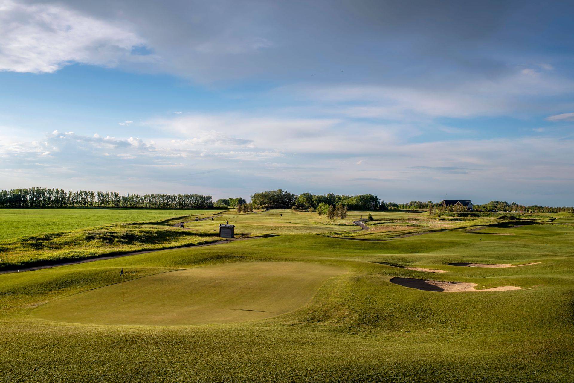 Golf course clubhouse at dusk, with water feature in the foreground and a moon in the sky.