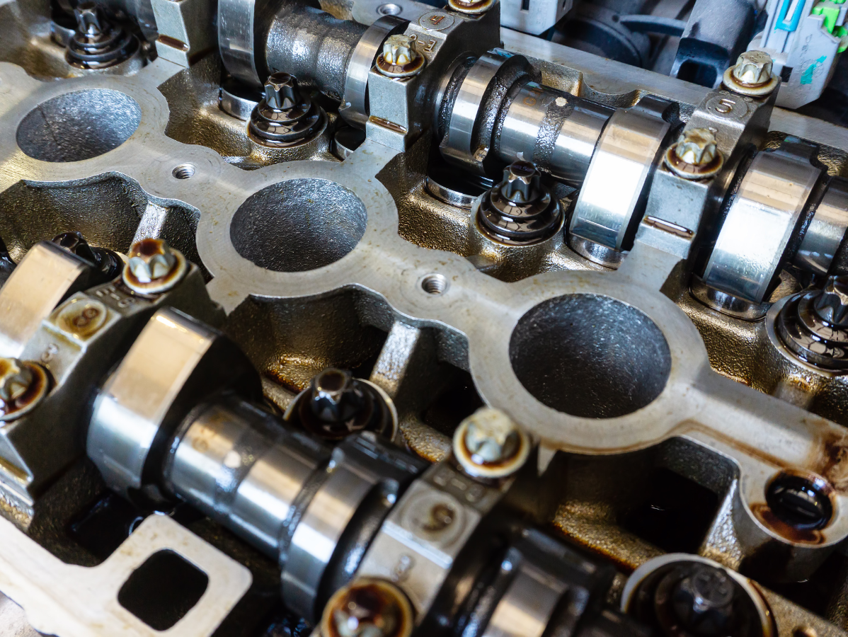 Engine cylinder head with camshafts, valves, and oil. Metallic parts, dark oil.
