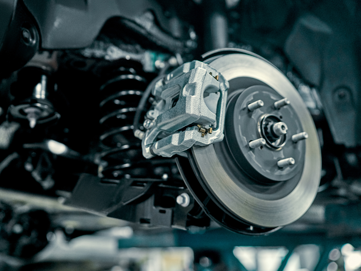 Car brake disc and caliper assembly, close-up view. Metallic components in a factory setting.