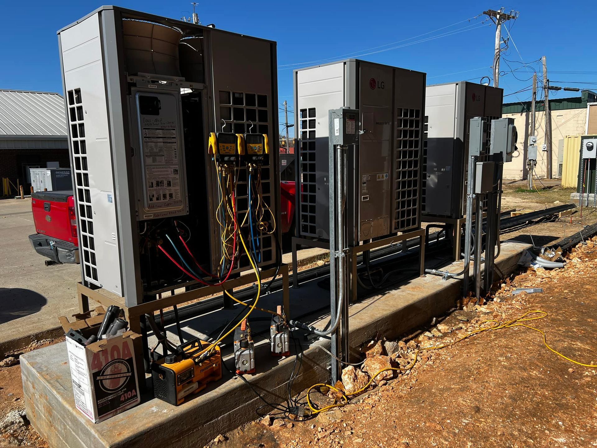 Electrical equipment installation outdoors, exposed wires and components, grey cabinets, brown ground, bright sunny day.