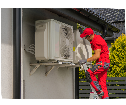 A person in red work clothes is installing an air conditioning unit on a house, using a ladder for access.