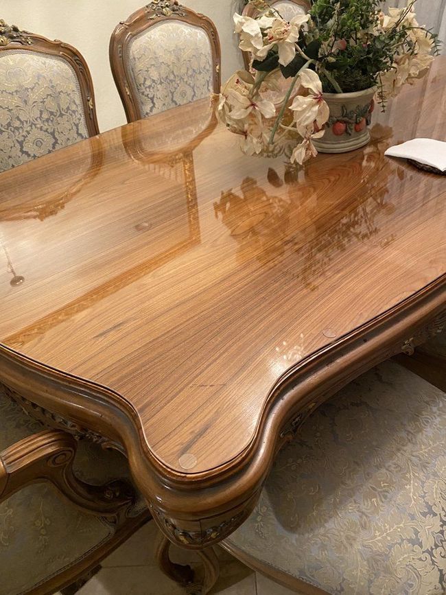 A dining room table with a vase of flowers on top of it.