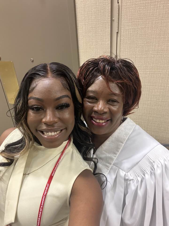 Two women are posing for a picture together and smiling for the camera.