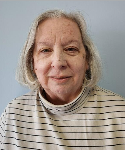 The woman is wearing a striped shirt and smiling for the camera.