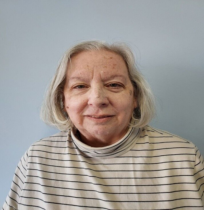 A woman is wearing a striped shirt and smiling for the camera.