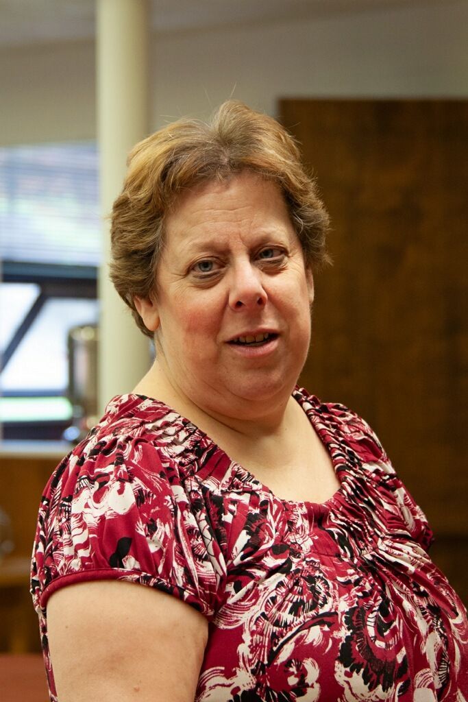 A woman is wearing a white jacket and holding a cup of coffee.