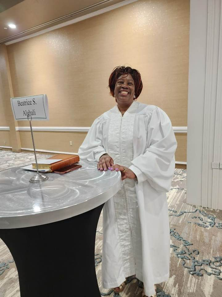 A woman in a white robe is standing next to a table.