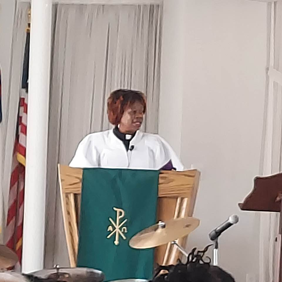 A woman is standing at a podium giving a speech in a church.