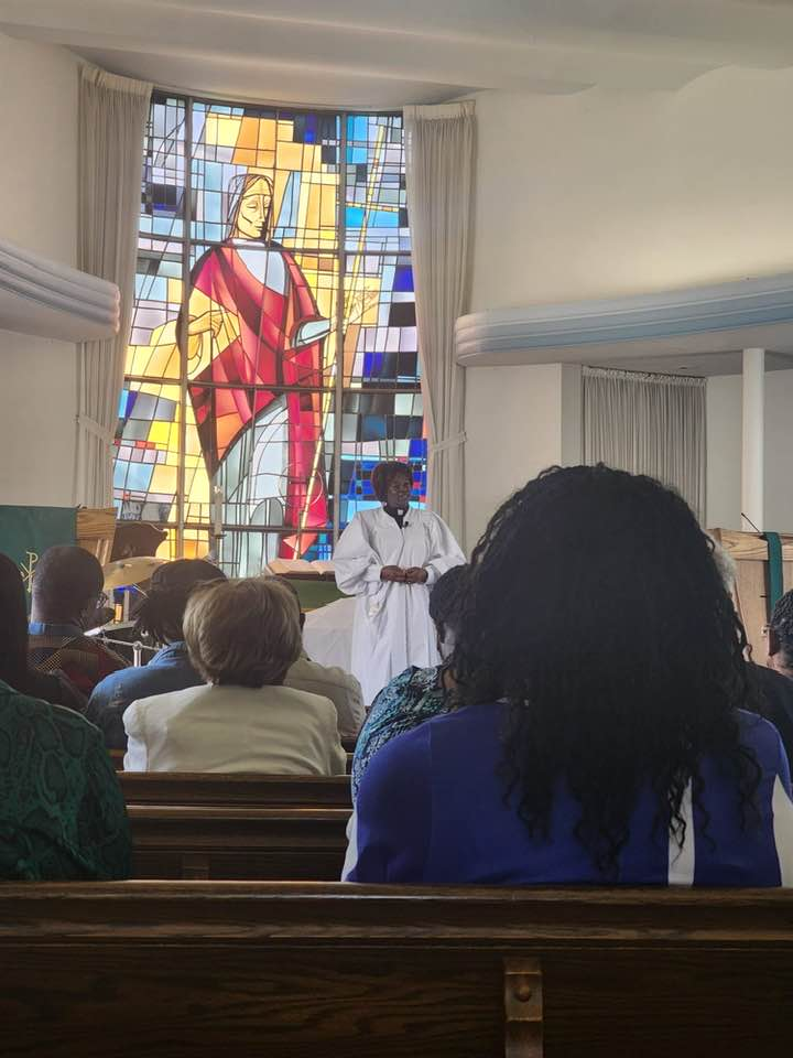 A man is standing in front of a stained glass window in a church.