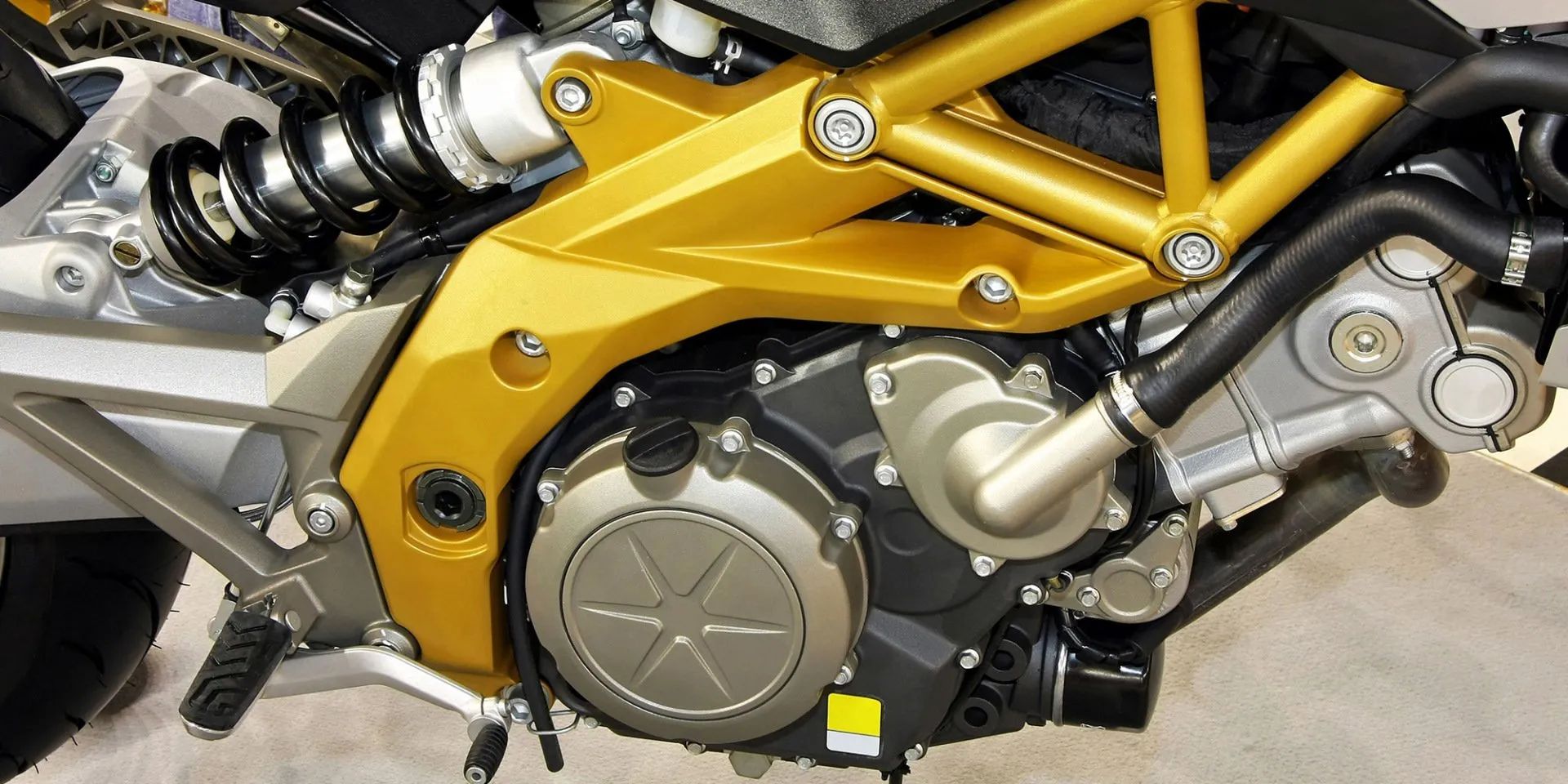 Close-up of a motorcycle engine, with a gold frame and black components.