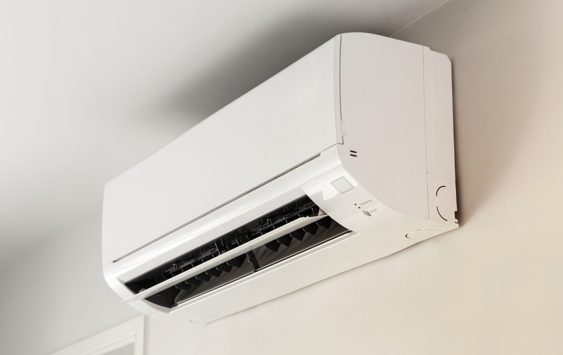 A white air conditioner is hanging from the ceiling in a room.