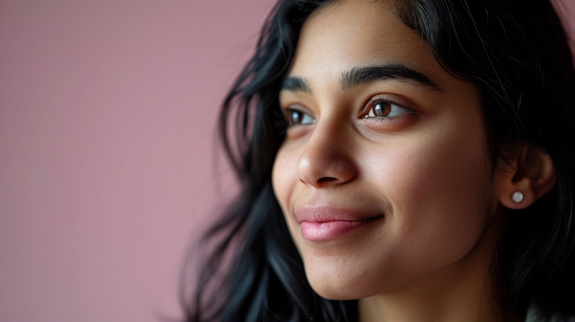 A close up of a woman 's face with a pink background.