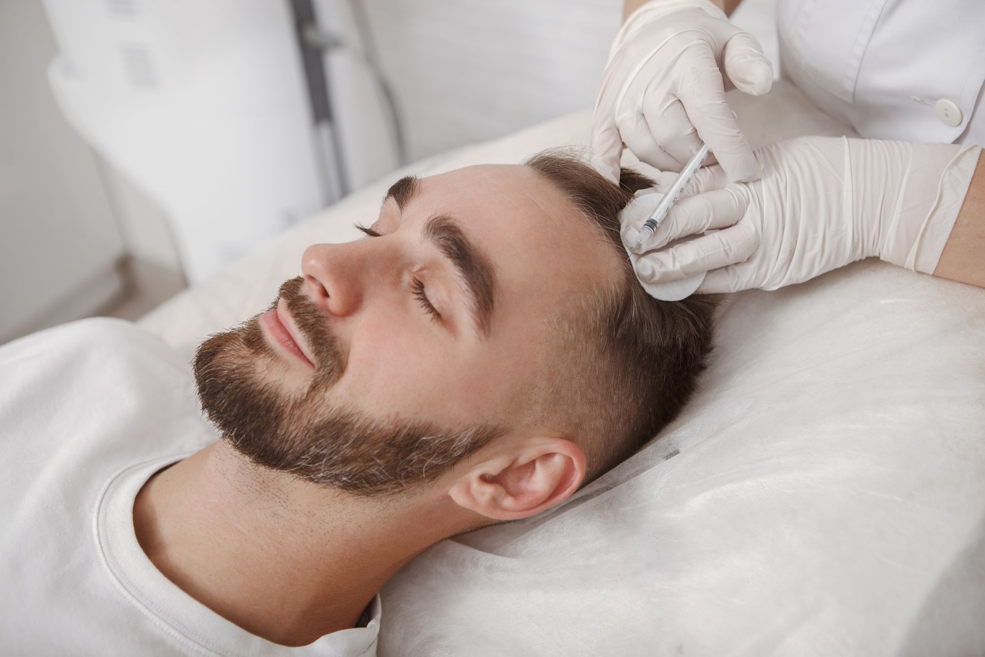 A man with a beard is getting a hair treatment.