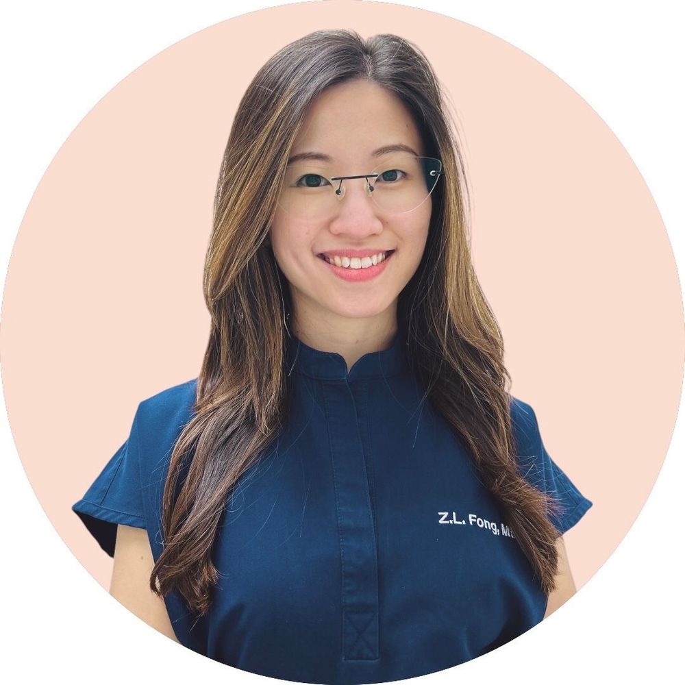 A woman in a blue scrub top is smiling for the camera.