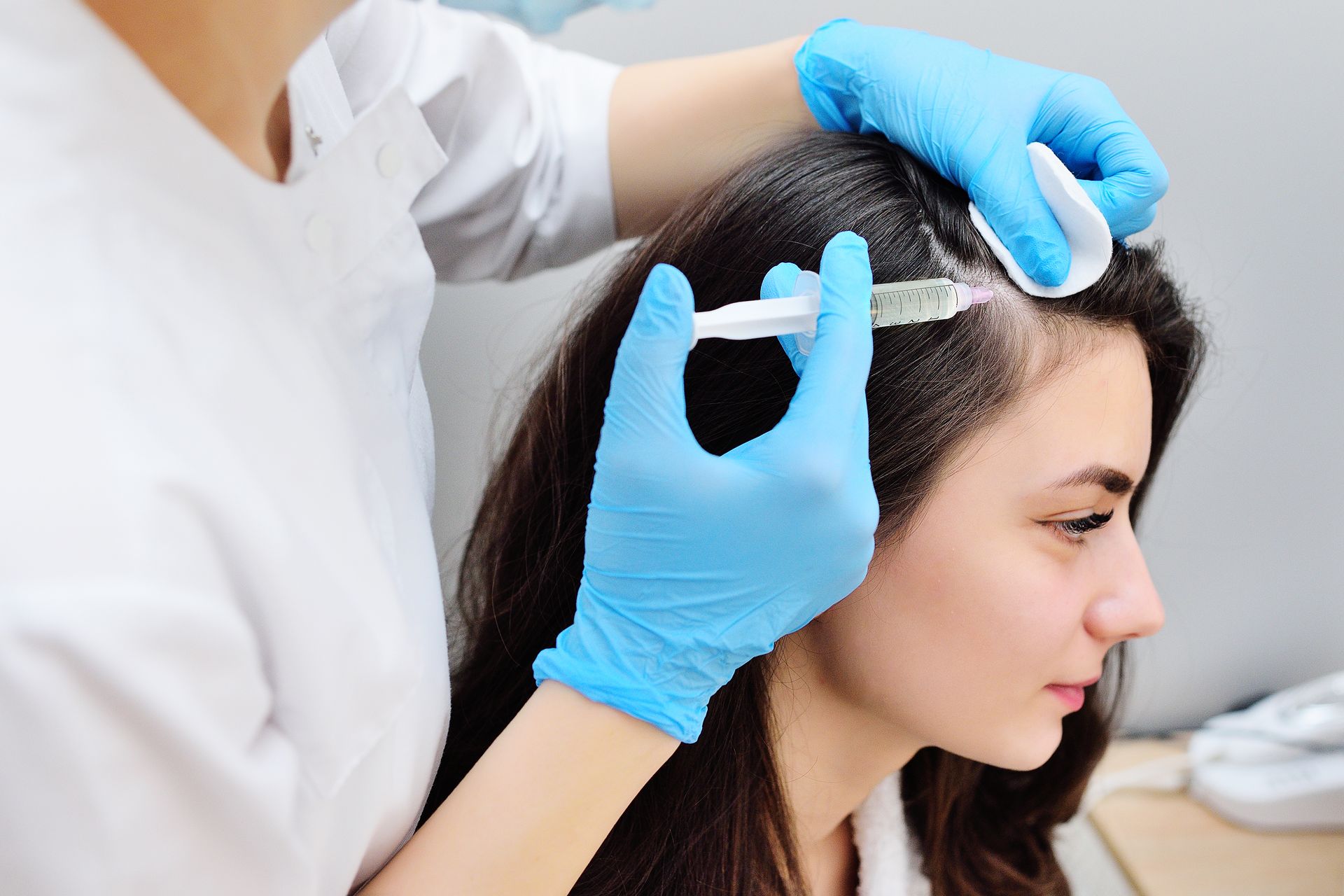 A woman is getting a hair treatment from a doctor.