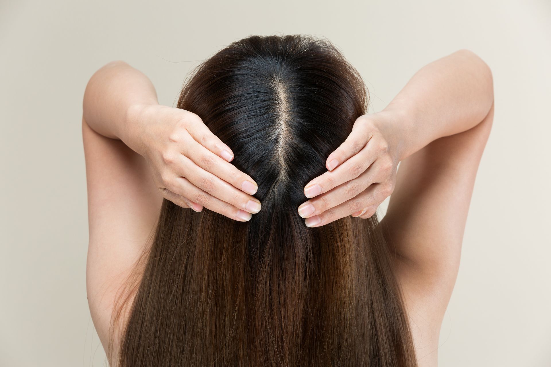 A woman is touching her hair with her hands.