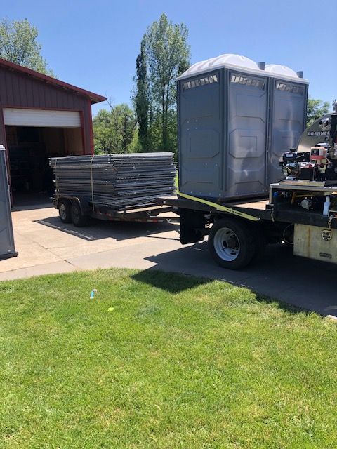 A tow truck is pulling a trailer with two portable toilets on it.