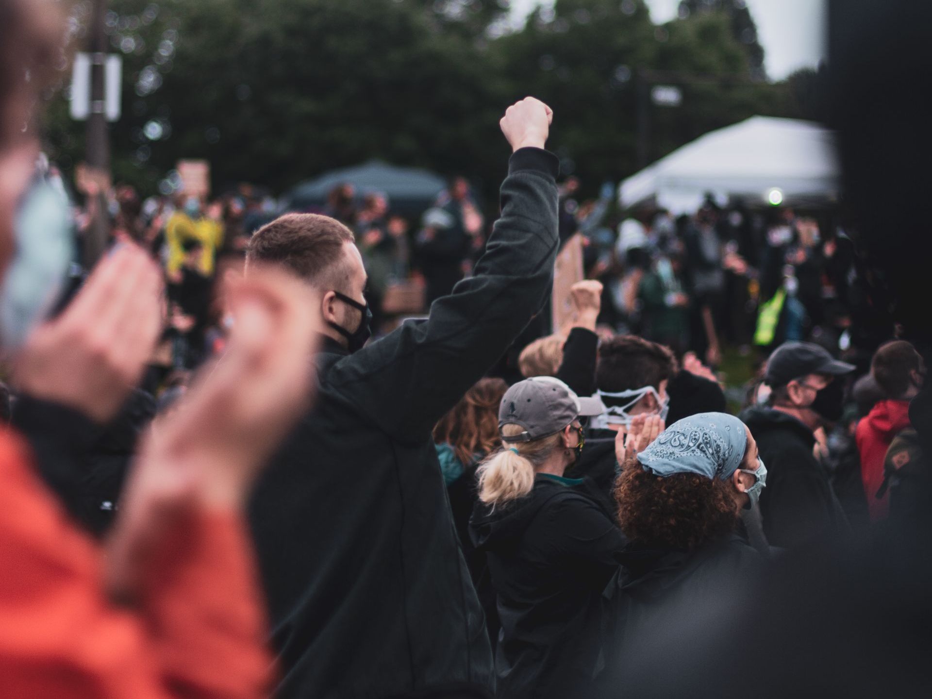 A group of people are standing in a crowd with their hands in the air.