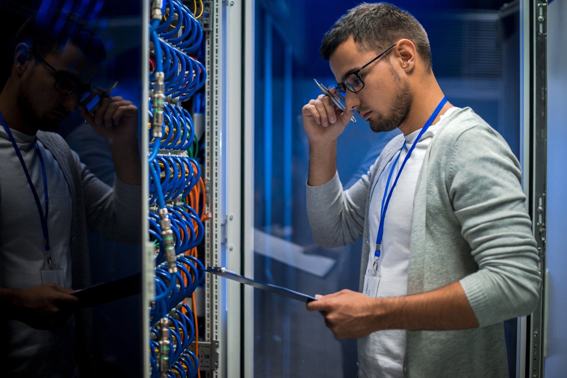 young man inspecting server rack and running diagnostics