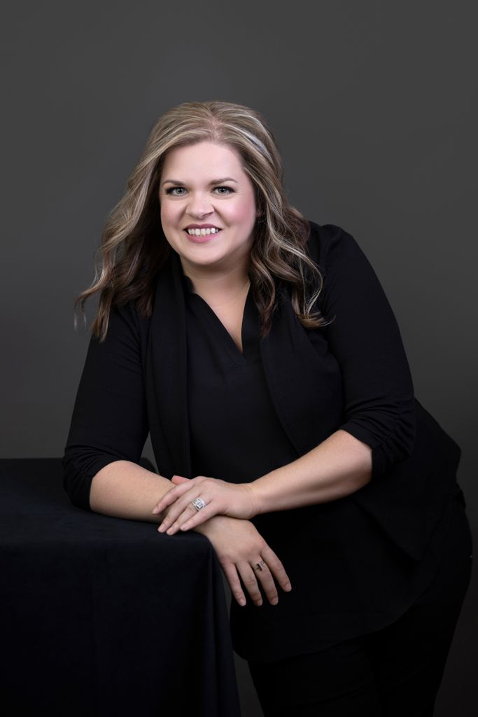 A woman in a black shirt is leaning on a table.