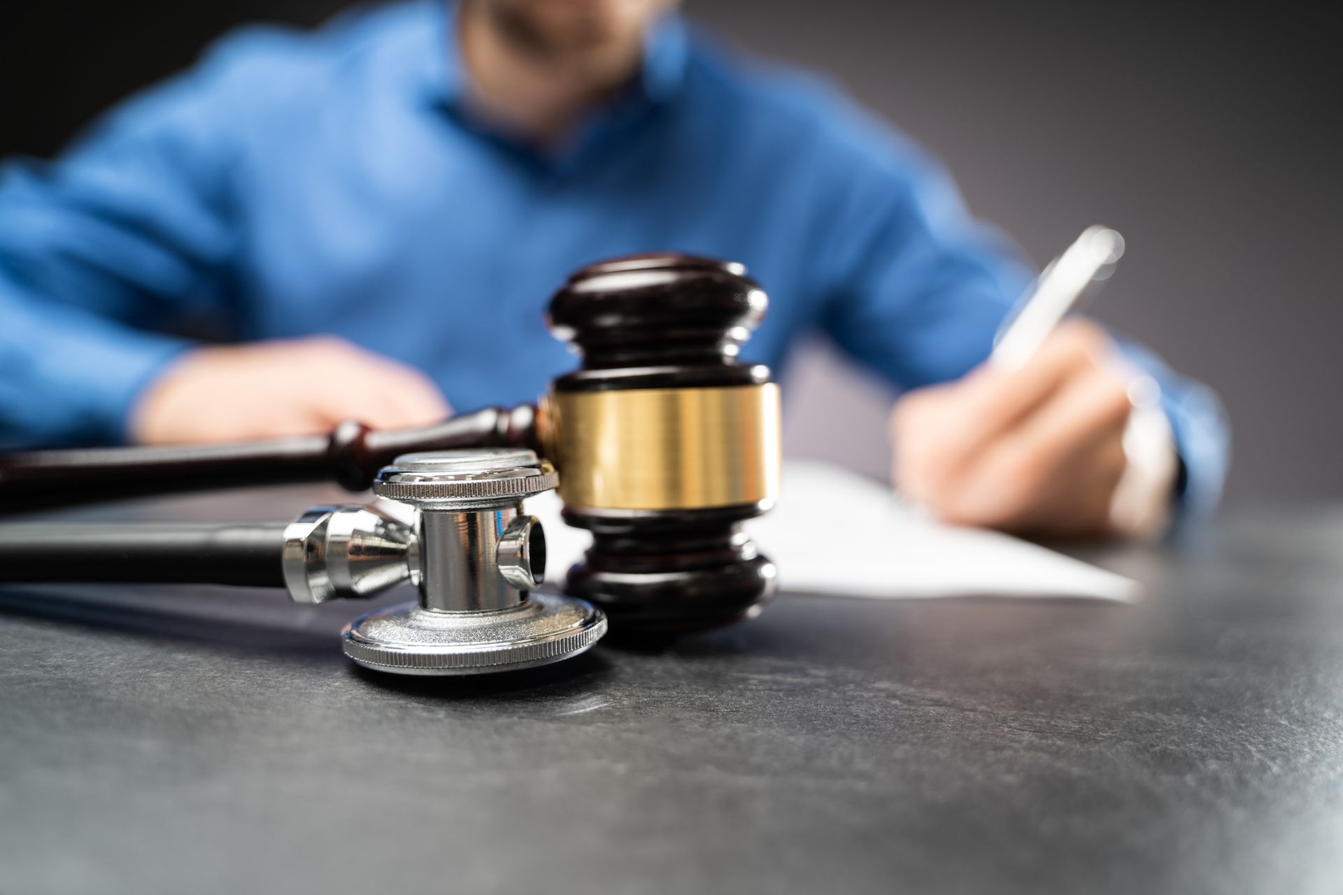 A man is sitting at a table with a stethoscope and a judge 's gavel.