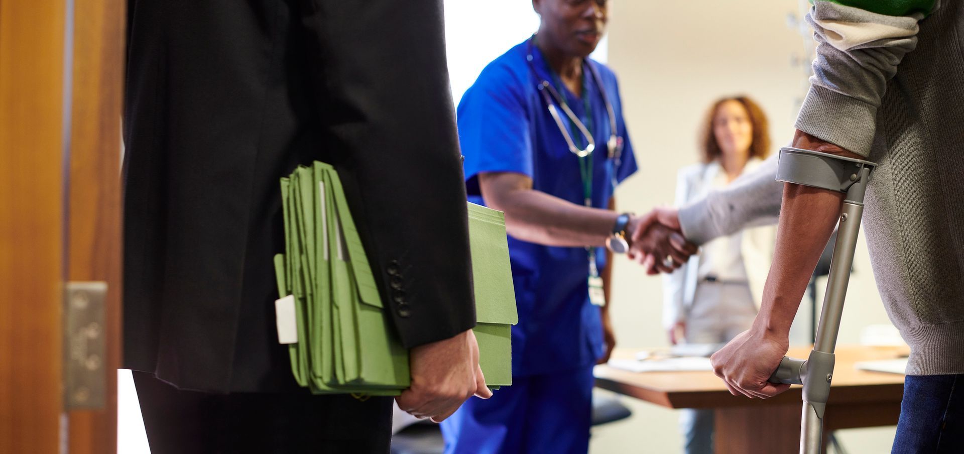 A man with crutches is shaking hands with a doctor.