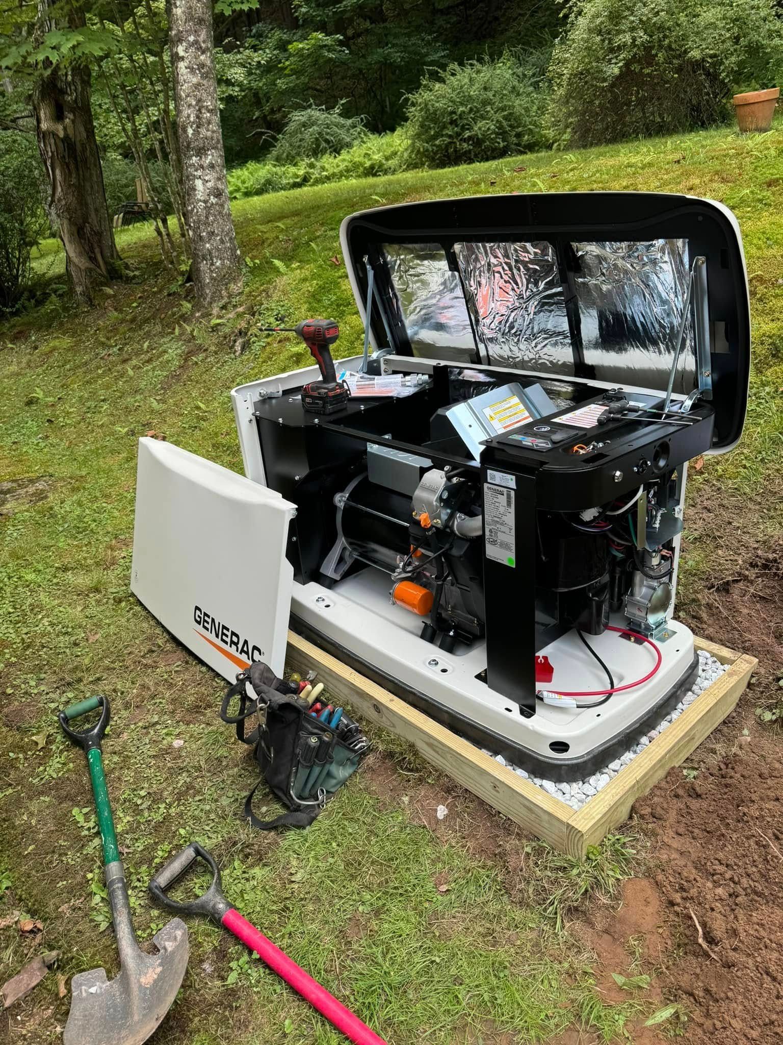 American Electric LLC | A generator is sitting in the grass next to a shovel.