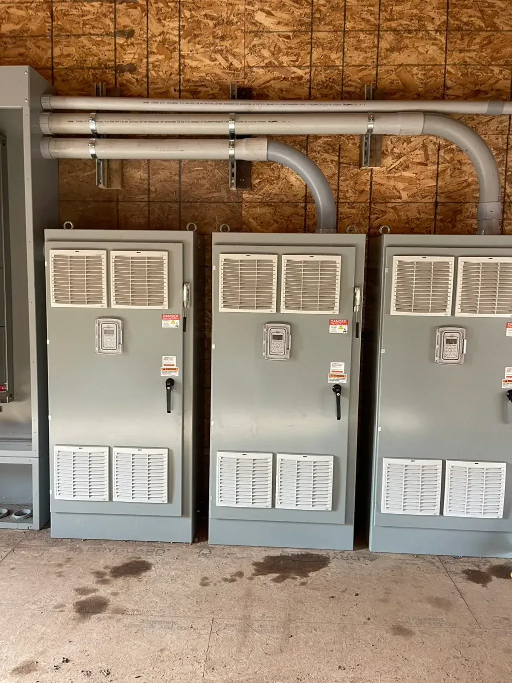 American Electric LLC | Three electrical boxes are lined up next to each other in a room.