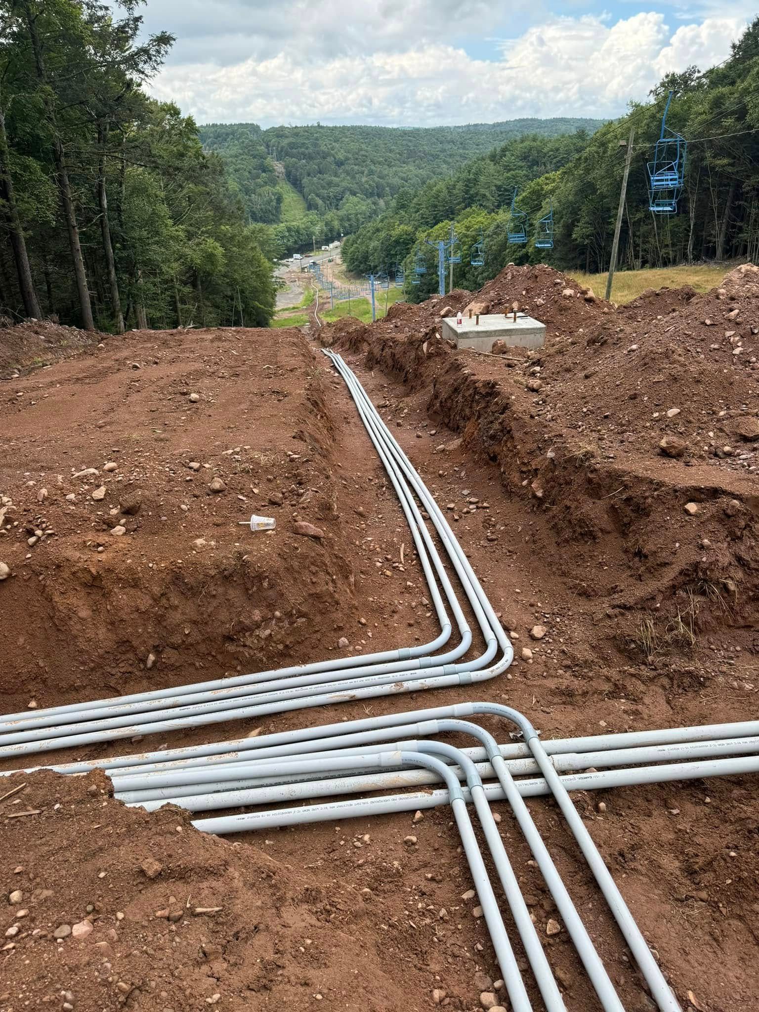 American Electric LLC | A bunch of pipes are laying in the dirt.