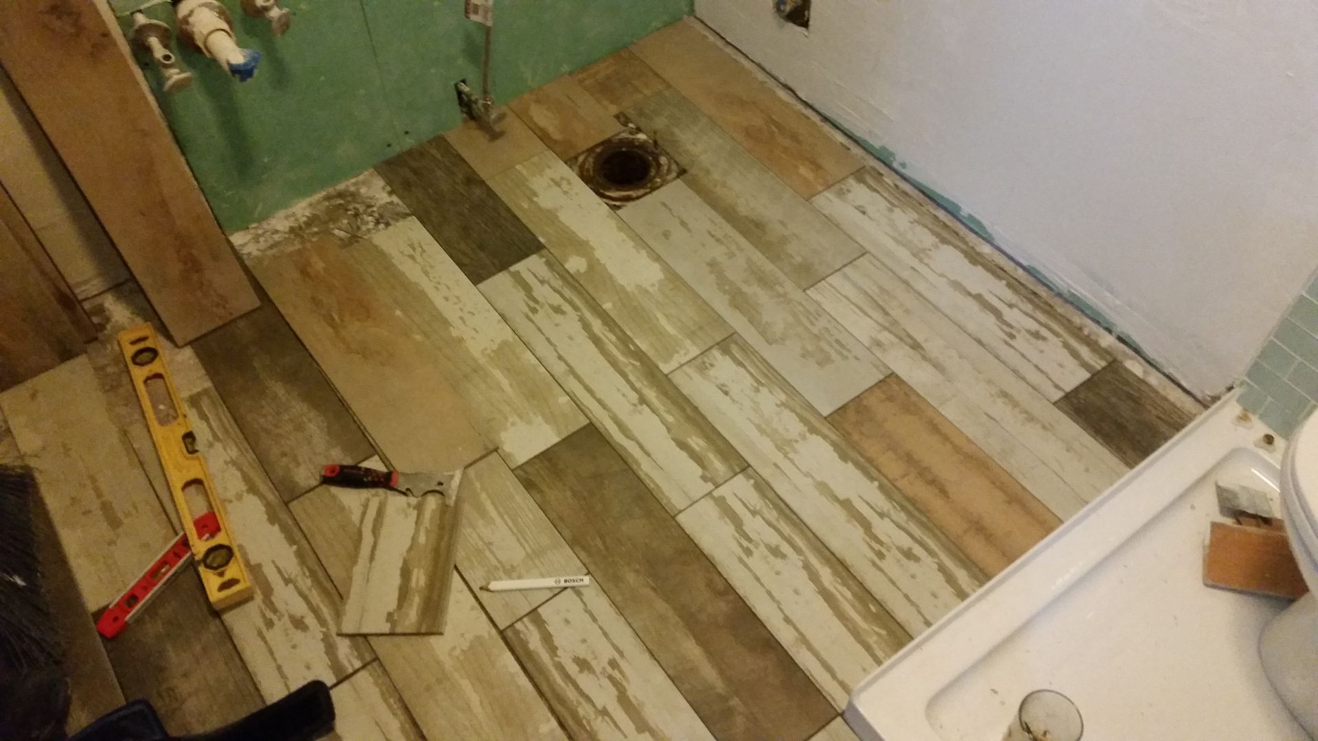 A bathroom with a wooden floor and a level on the floor.