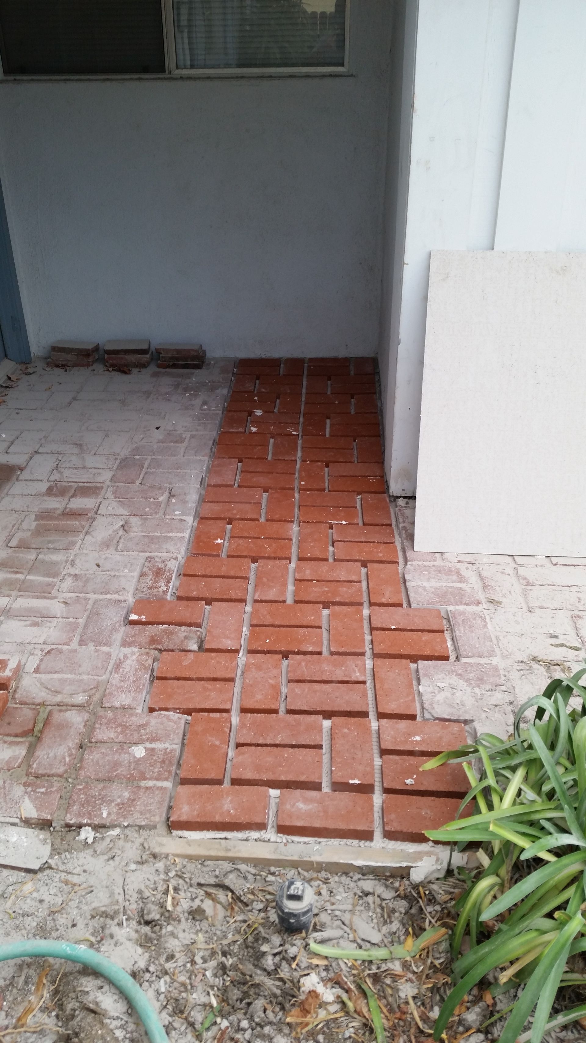 A brick walkway is being built in front of a house.