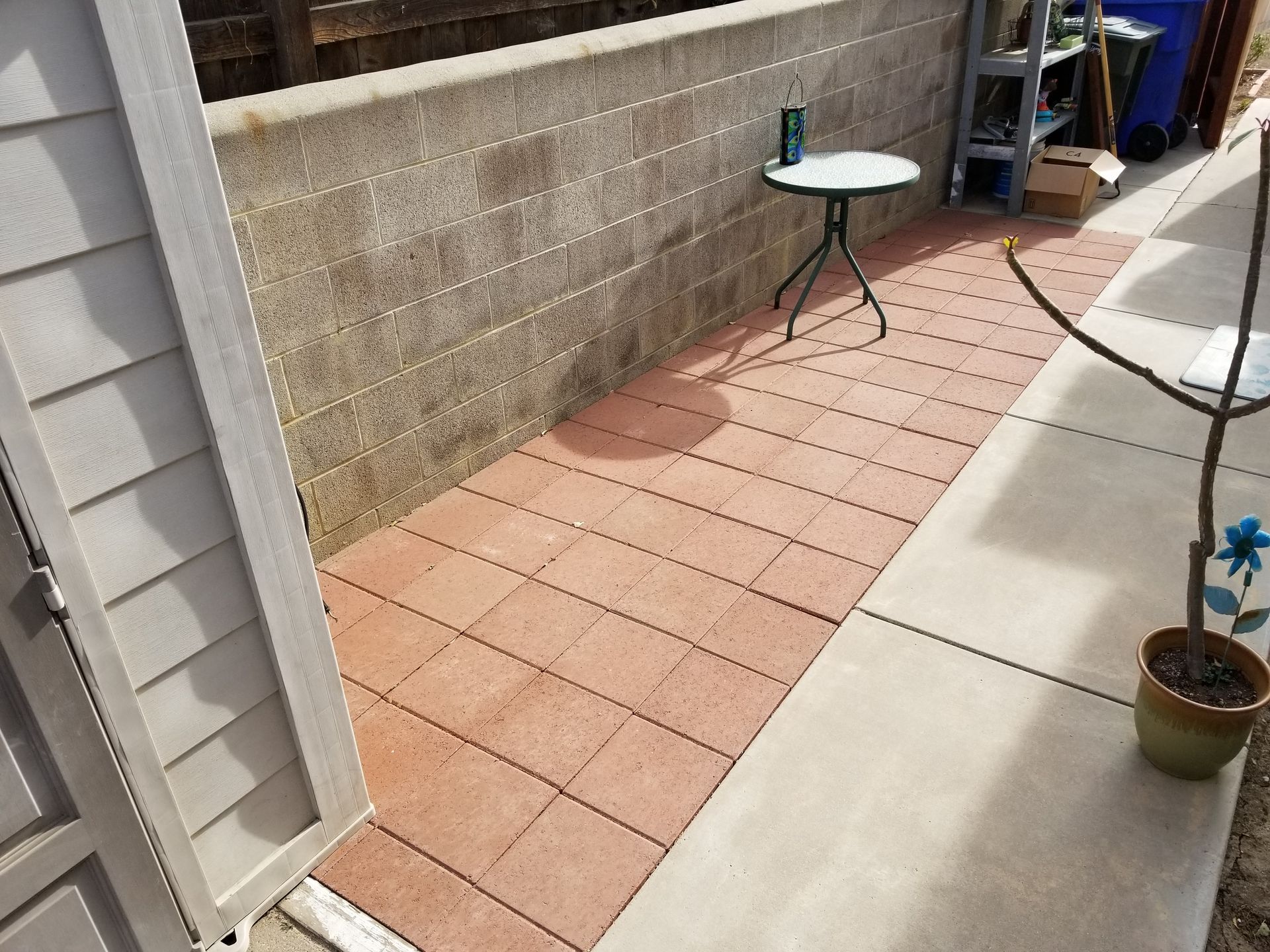A brick walkway with a table and a potted plant