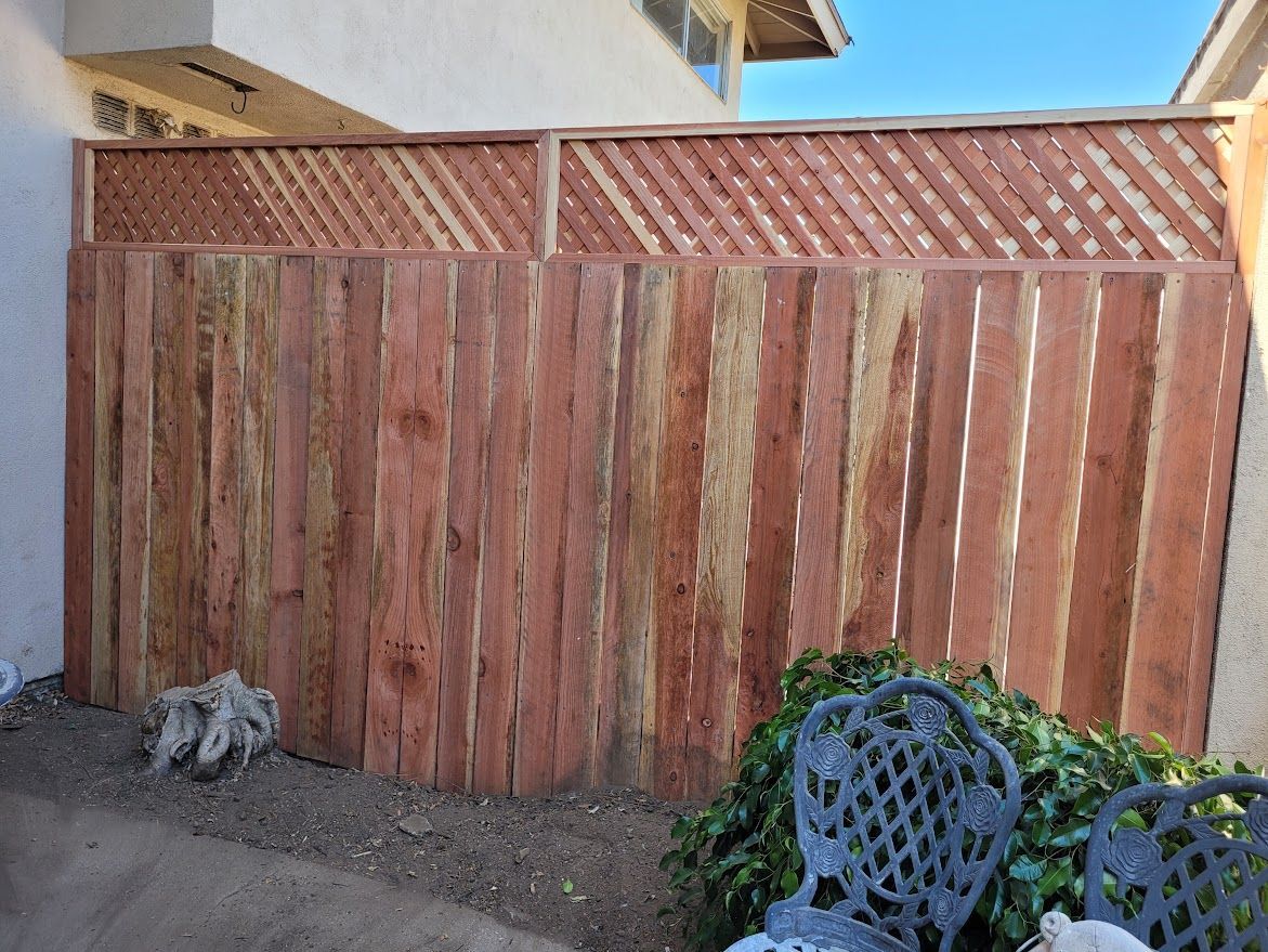 A wooden fence is in the backyard of a house.