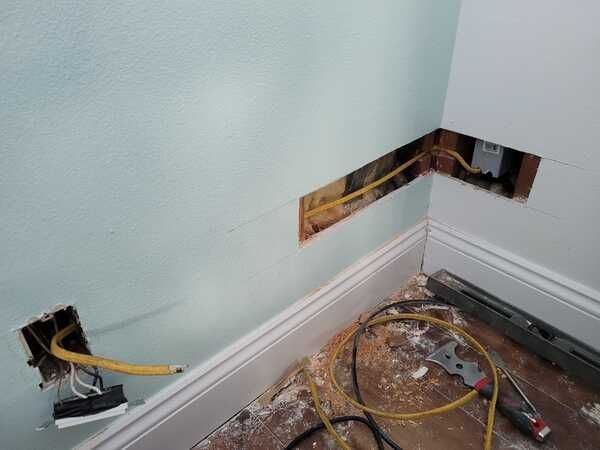 A corner of a room with electrical wires coming out of the wall