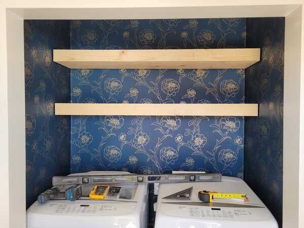 A laundry room with two washing machines and shelves