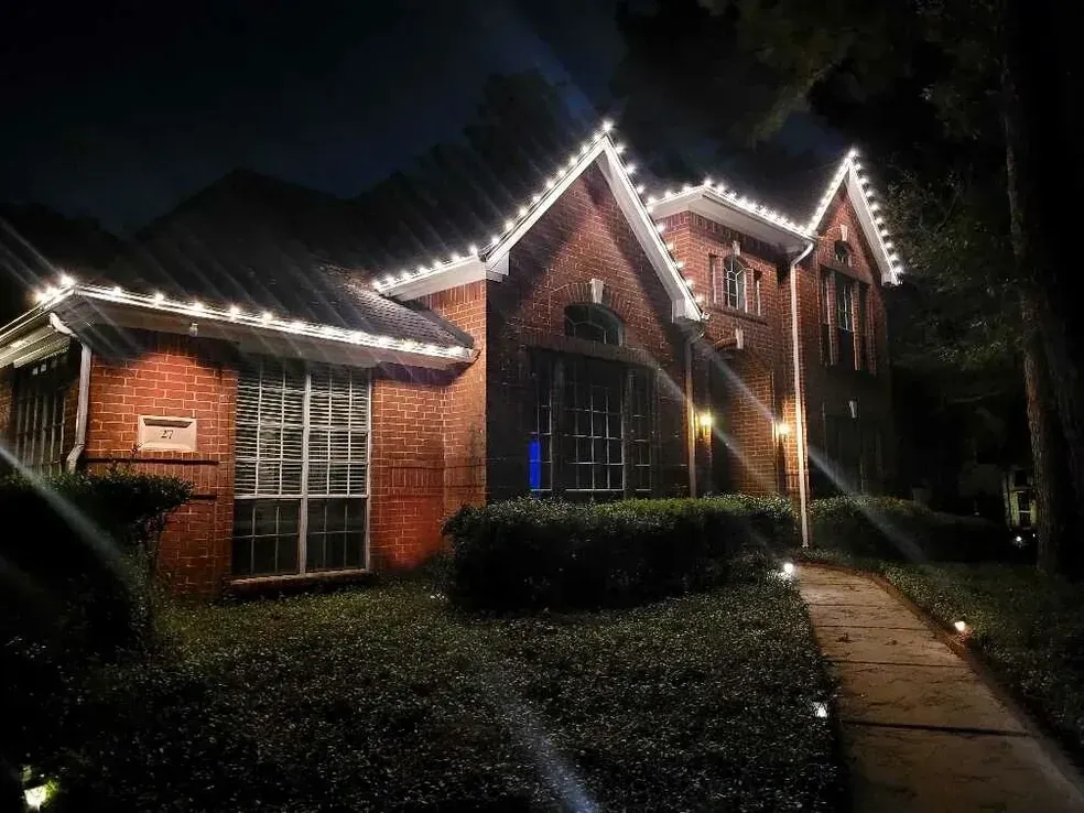 A brick house with christmas lights on the roof at night.