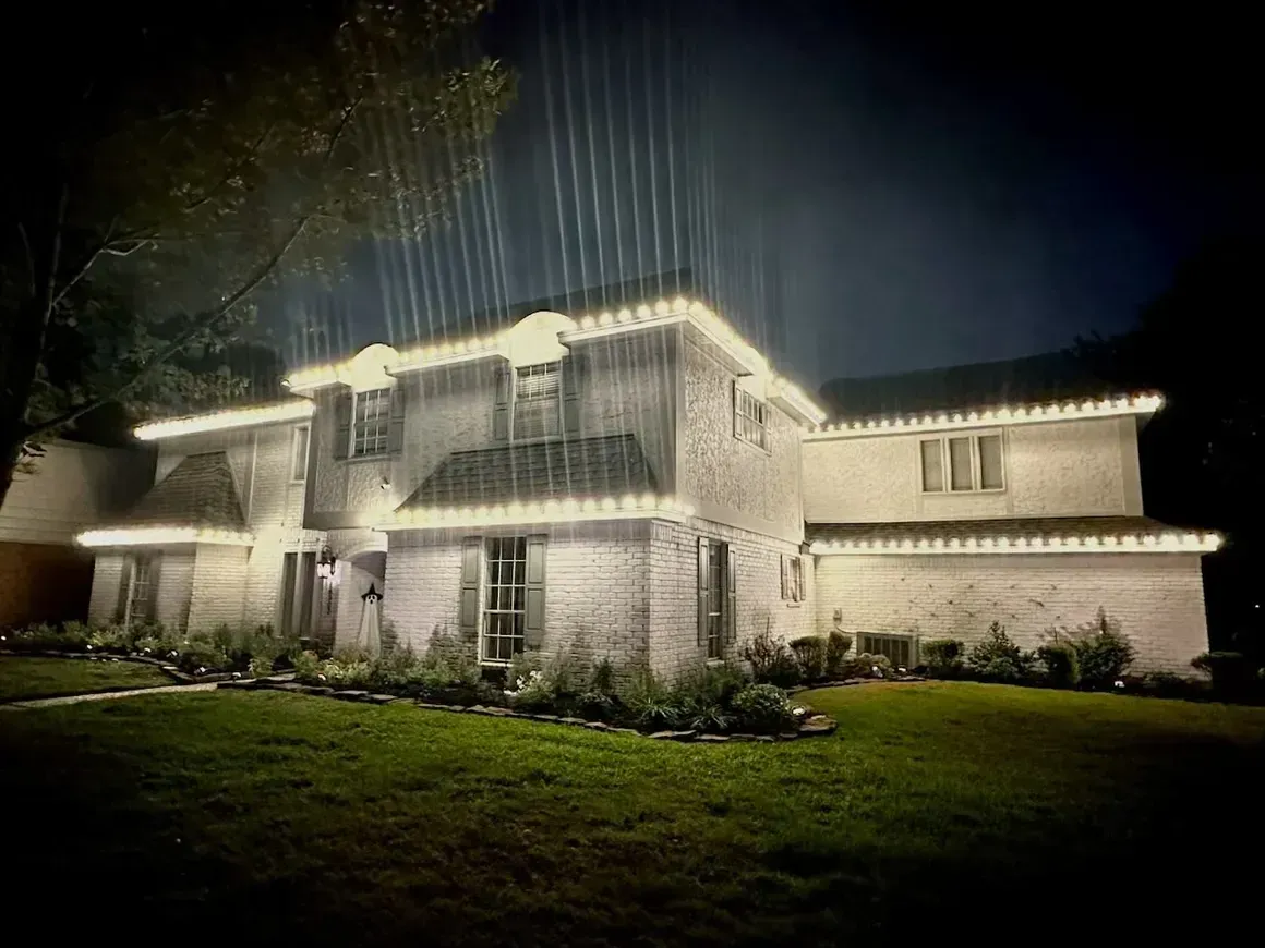 A house with christmas lights on it is lit up at night.