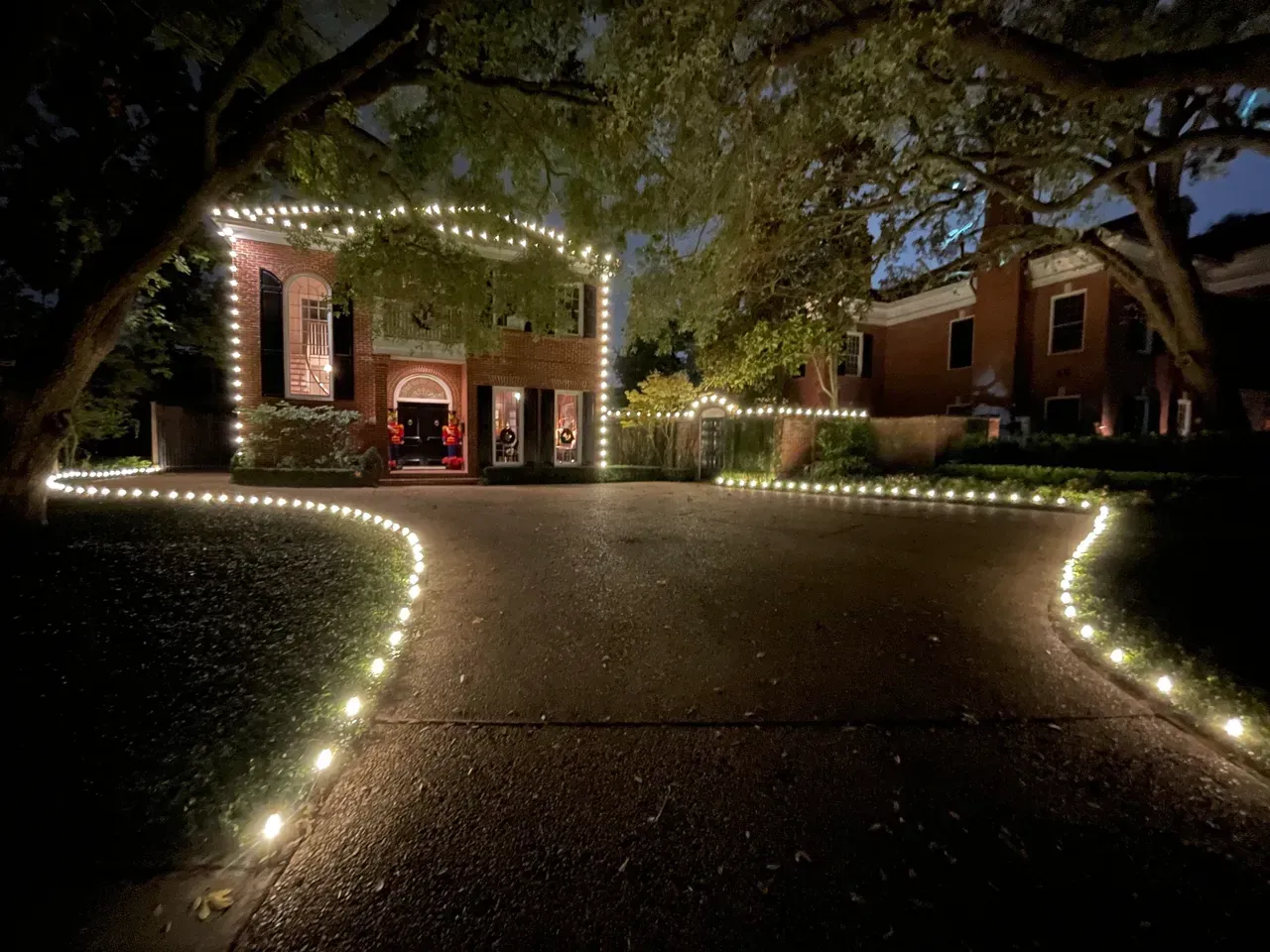 The driveway of a house is decorated with christmas lights.