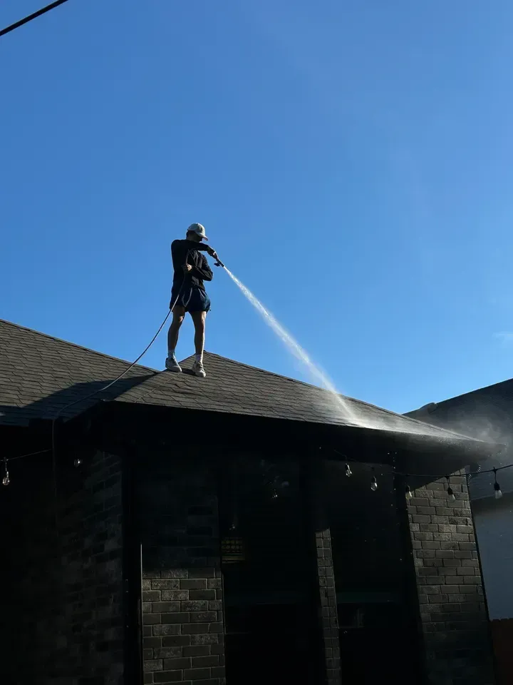 A man is spraying water on the roof of a house